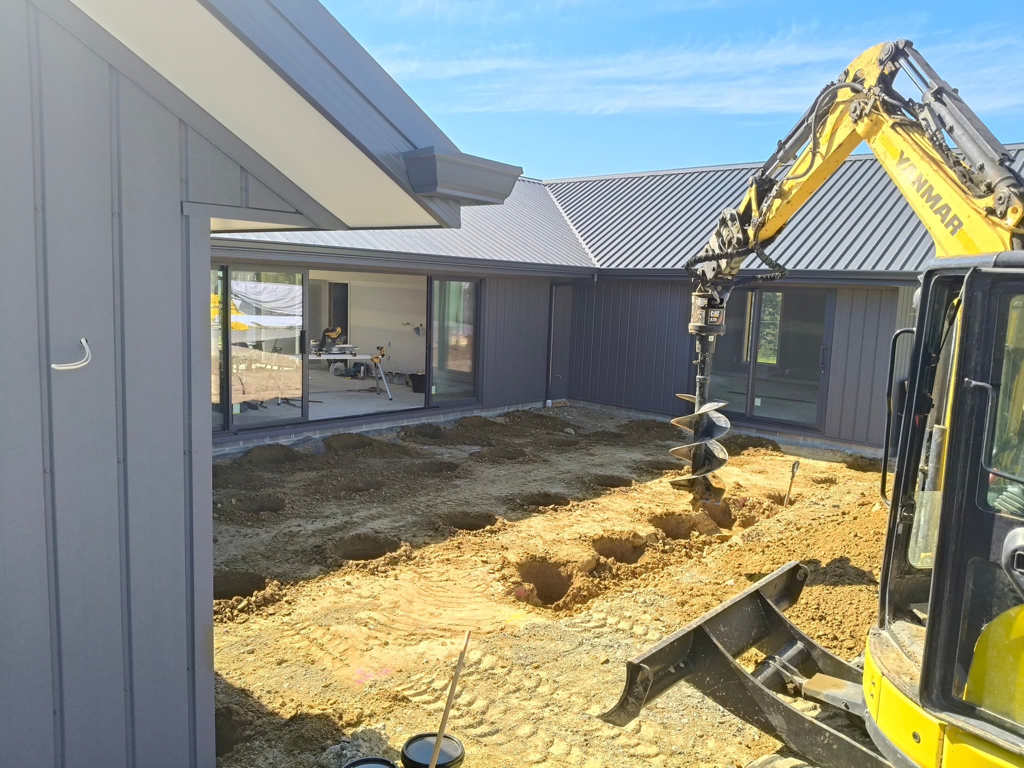 Yanmar excavator auger drilling post holes at new build