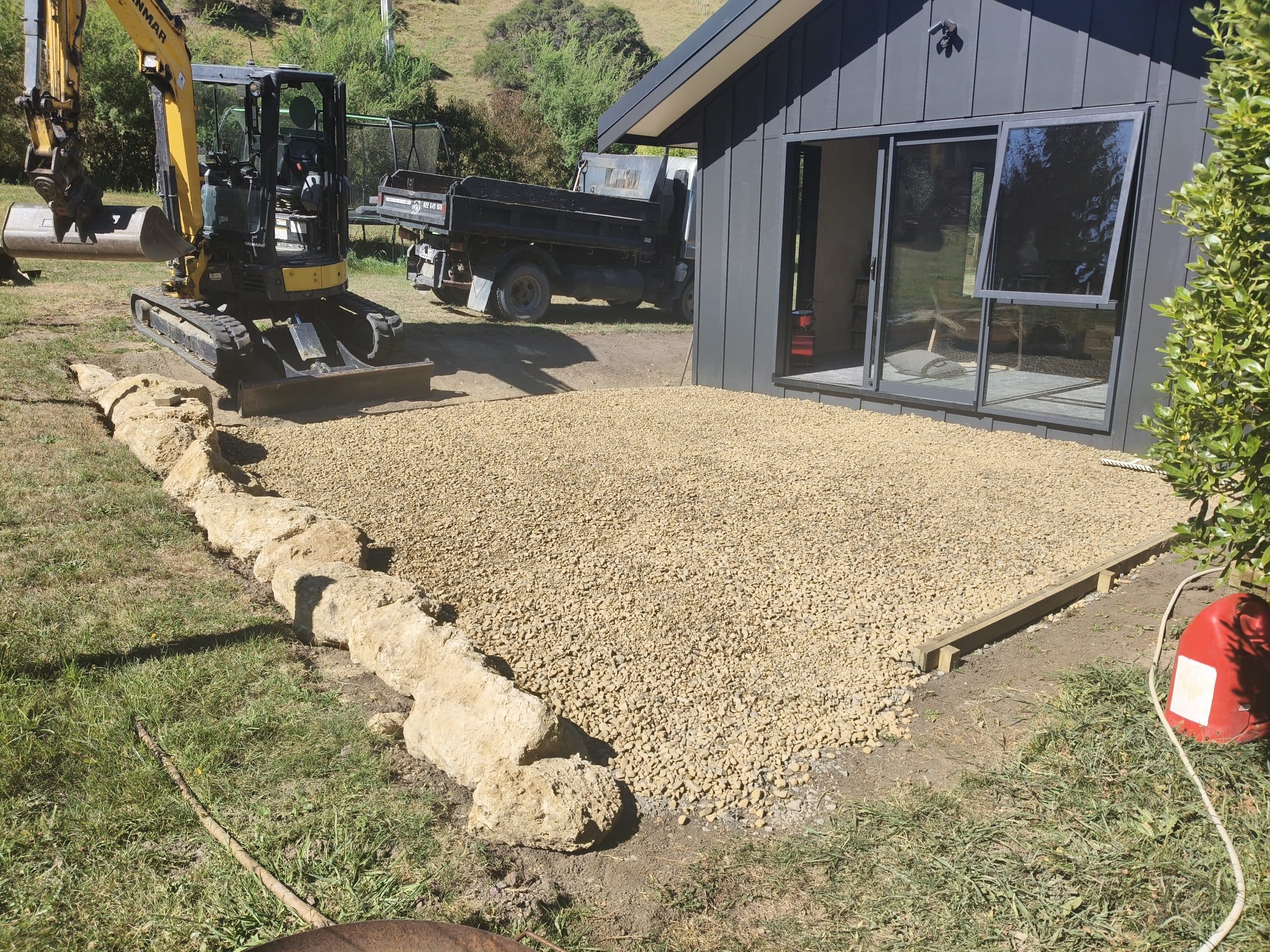 Gravel driveway completed next to modern dark barn-style home