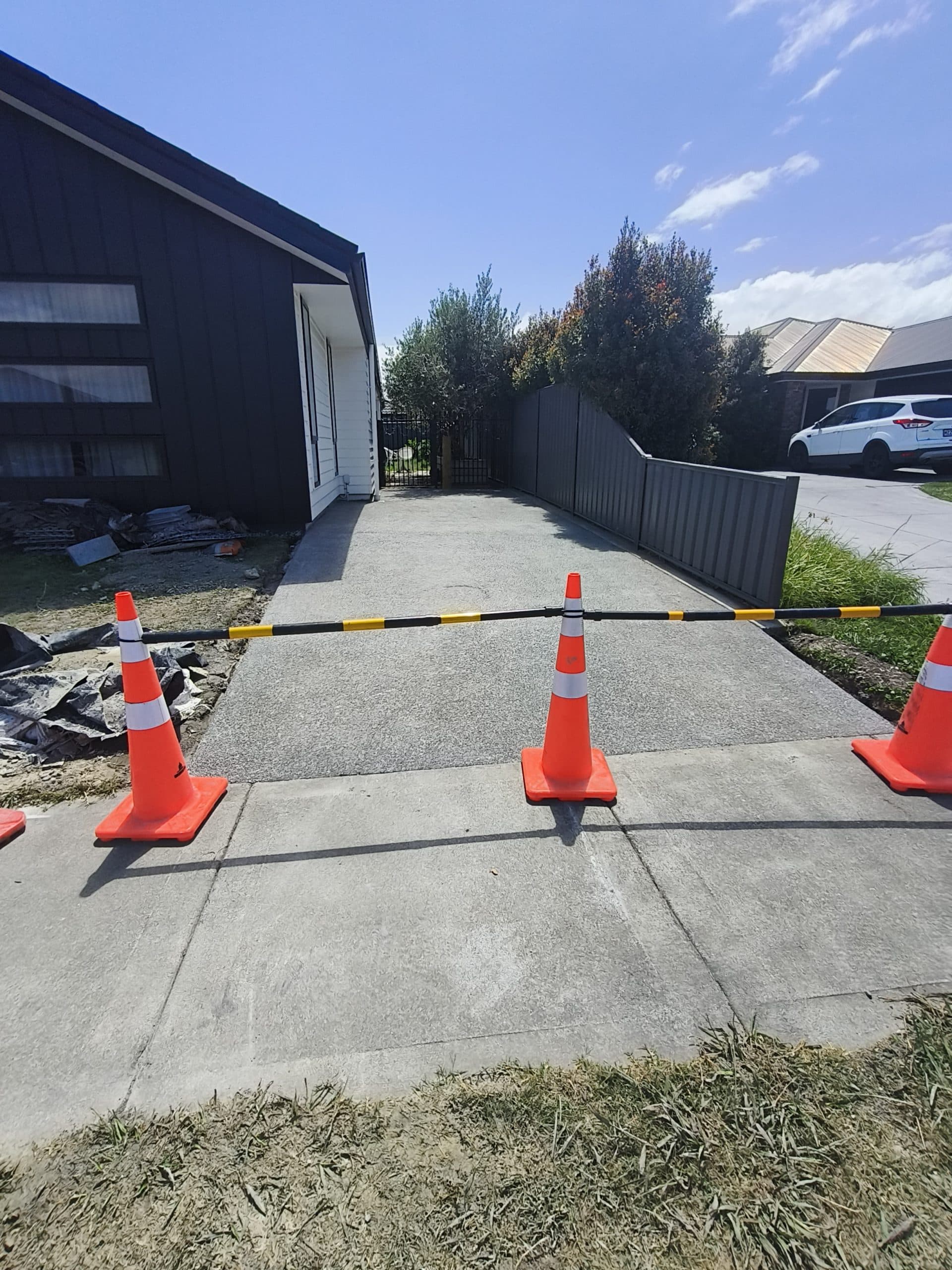 Freshly poured concrete driveway path with traffic cones