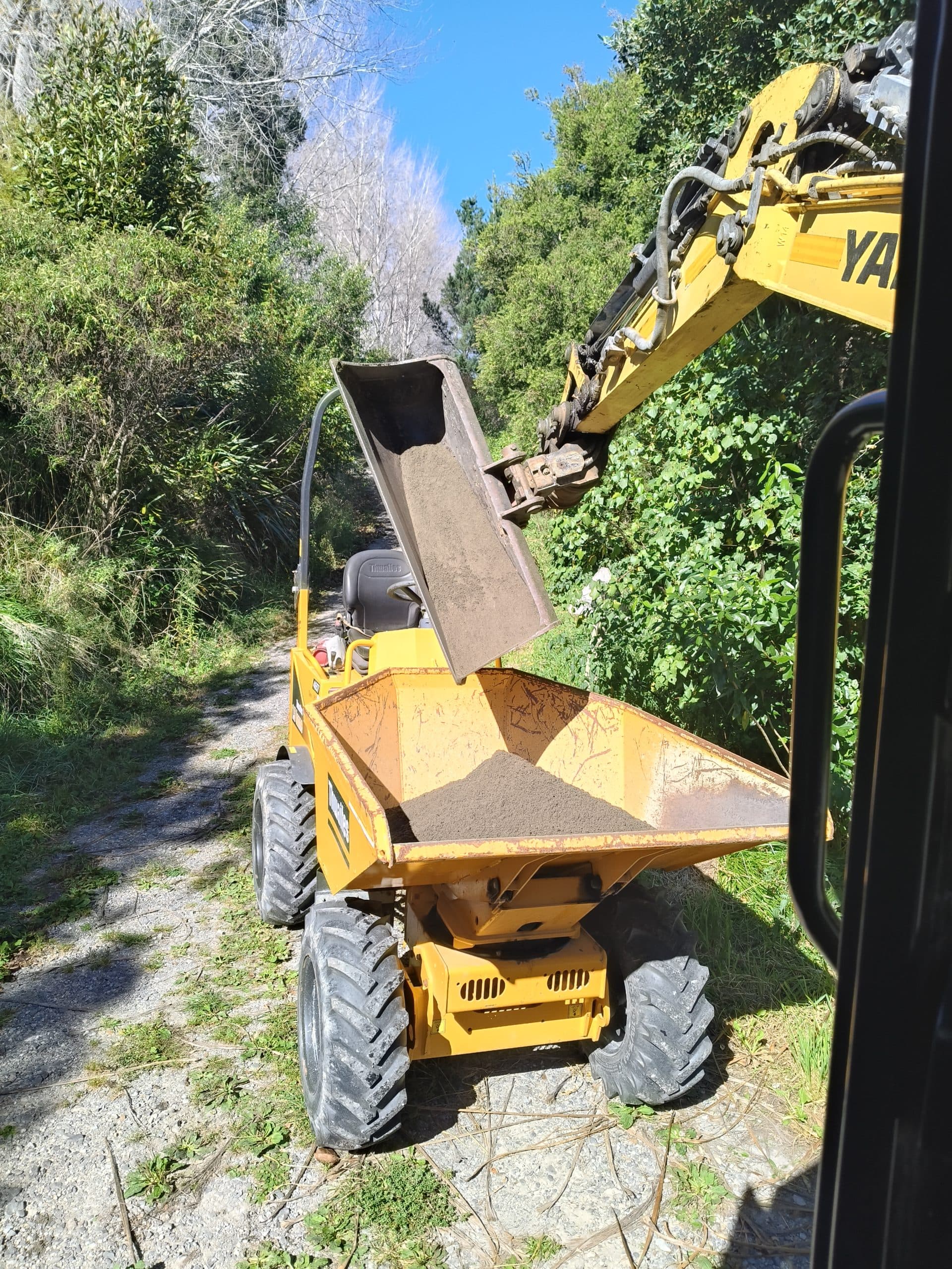 Yanmar excavator loading dumper truck on access track