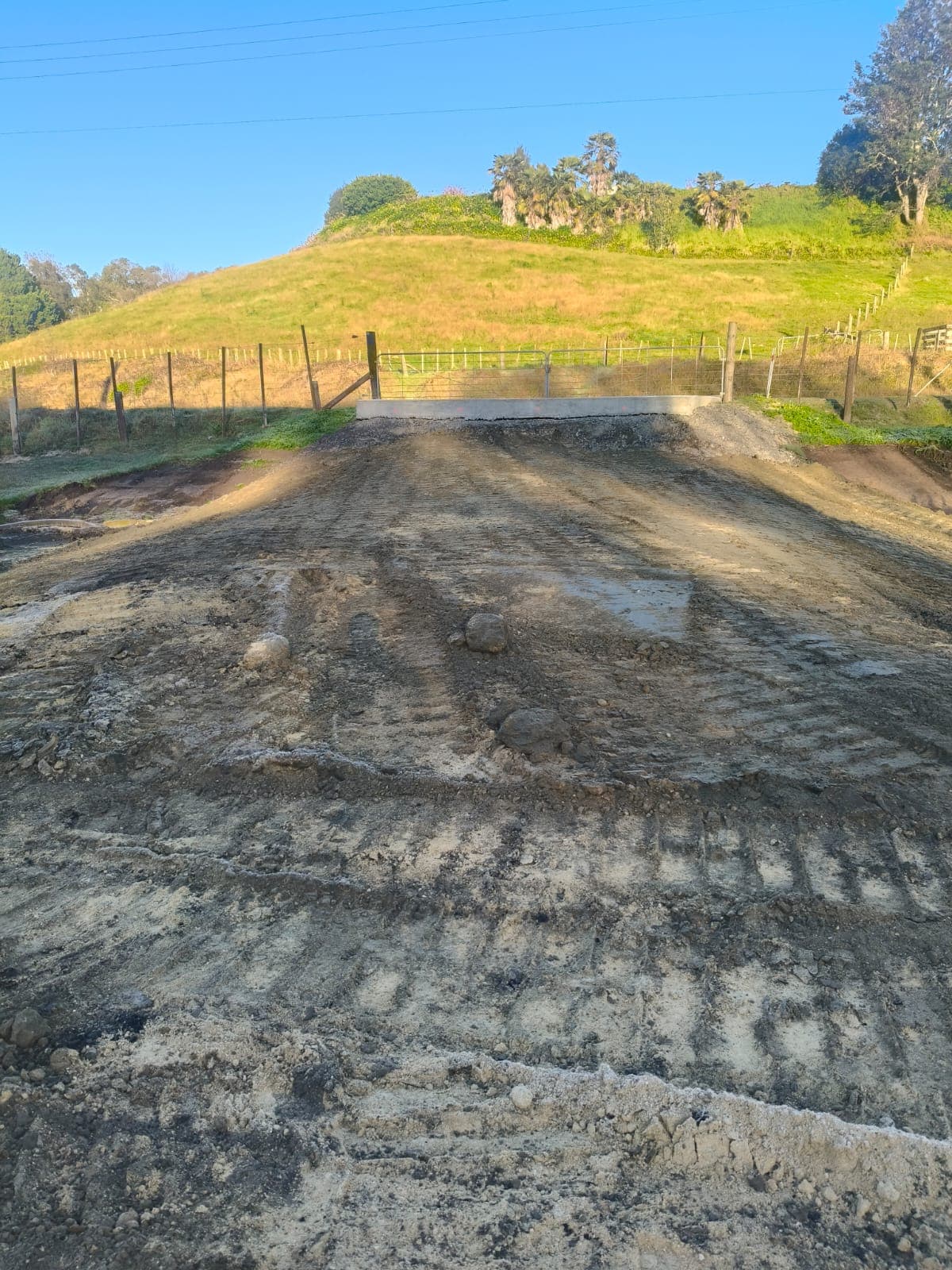 Graded dirt access ramp leading up to a concrete culvert and farm gate