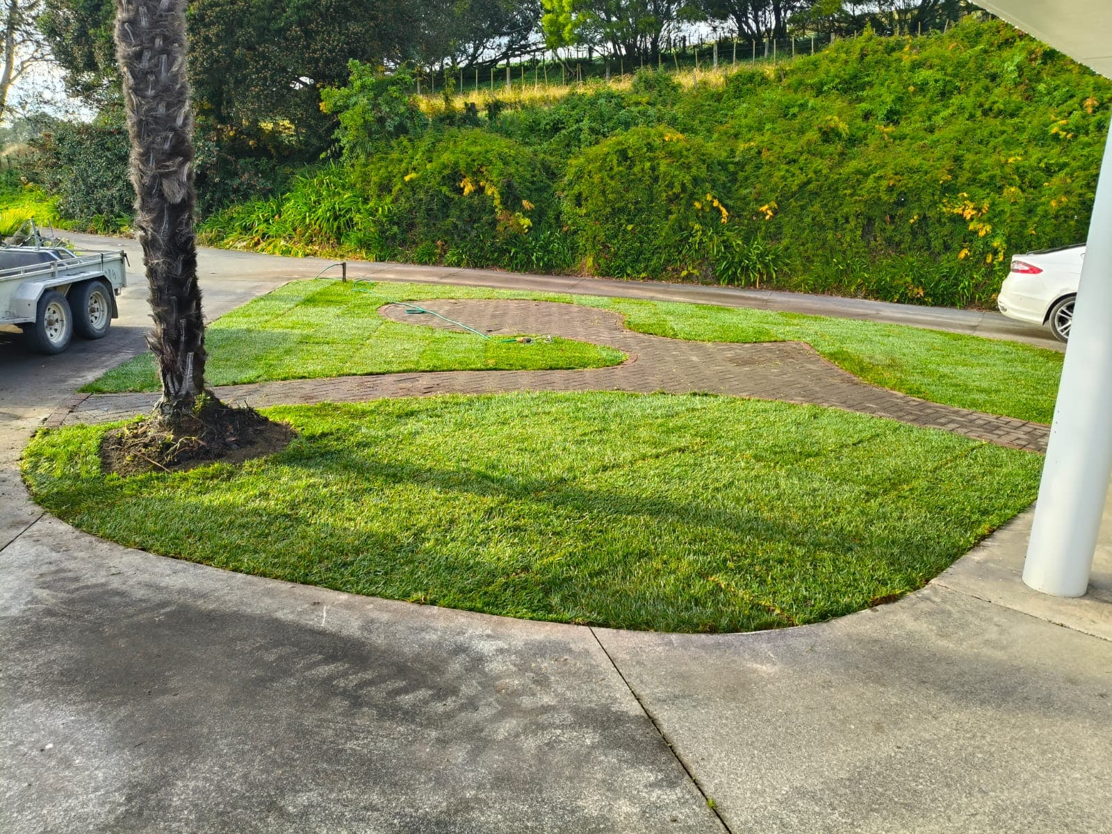 New green lawn framing the brick paver pathway and circular feature