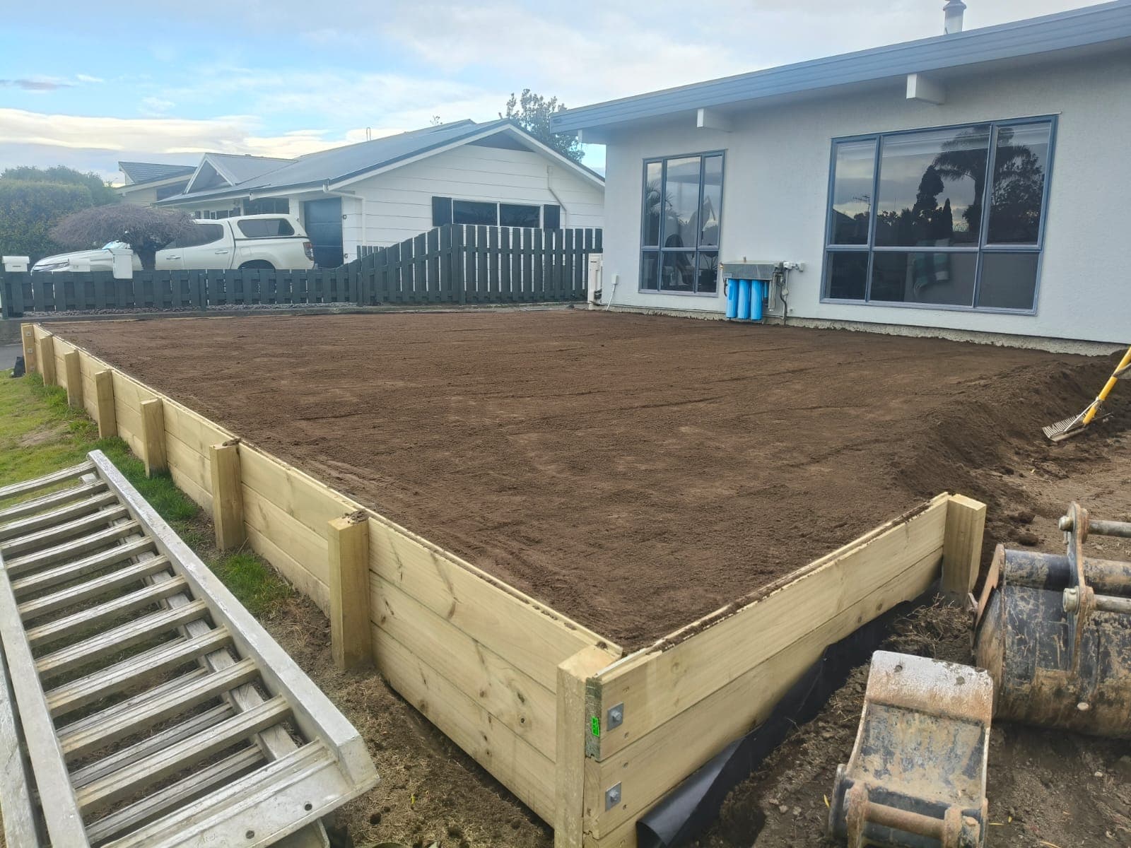 Levelled topsoil area enclosed by a new timber retaining wall ready for lawn