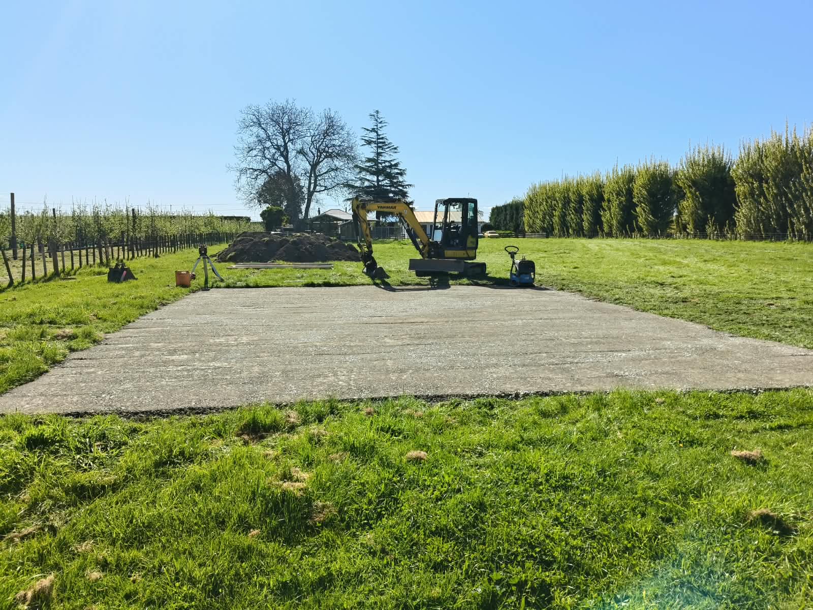 Excavator and truck staged beside a prepared concrete access area
