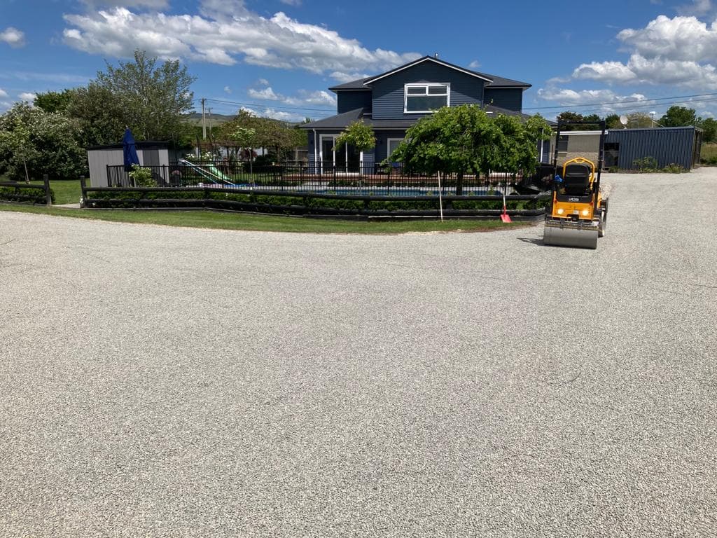 Finished gravel driveway with roller compactor at residential property