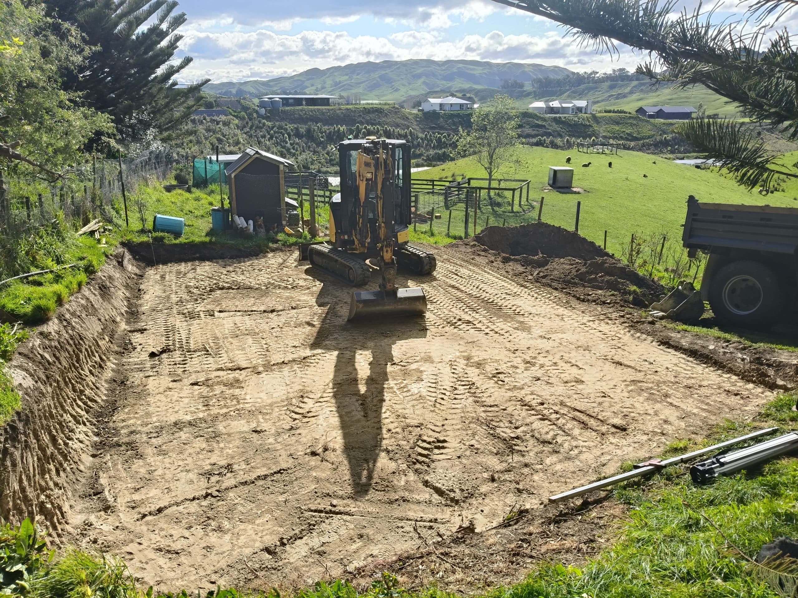 CAT mini excavator grading a rural site with Hawke's Bay hills in the background