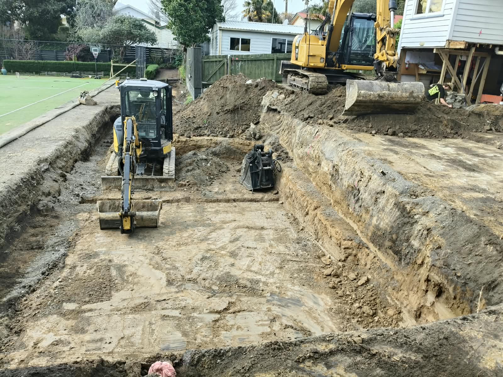 Excavated pit with a Yanmar excavator working below and a CAT excavator above